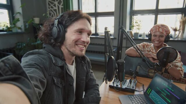 UGC POV footage of Caucasian male podcast host filming himself on camera and talking to African American female guest with guitar after recording in studio