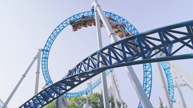 Roller coaster Ride against blue sky. Roller coaster in the amusement park. Cheerful entertainments in park of attractions