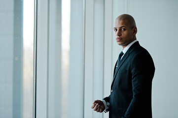Fototapeta premium African american businessman in formal wear looking at camera near window in office