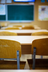 Classroom with empty chairs and blackboard in the background, shallow depth of field