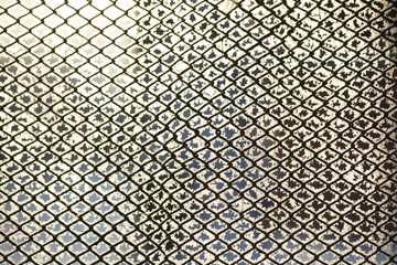 Natural wallpaper, fragment of a mesh fence in frost on a sunny winter day.