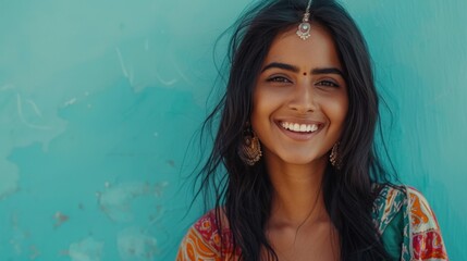 Beautiful young woman with radiant smile adorned with traditional jewelry against vibrant turquoise backdrop.