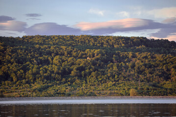 A large lake with calm waters at the edge of a picturesque tall forest in a village far from the cities
