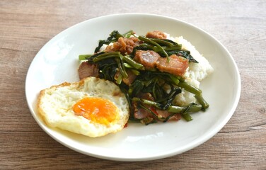 fried morning glory with crispy pork on rice topping egg in plate