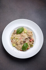 Risotto with meat, tomato and basil on a dark background