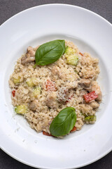 Risotto with meat, tomato and basil on a dark background