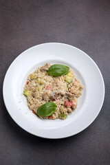 Risotto with meat, tomato and basil on a dark background