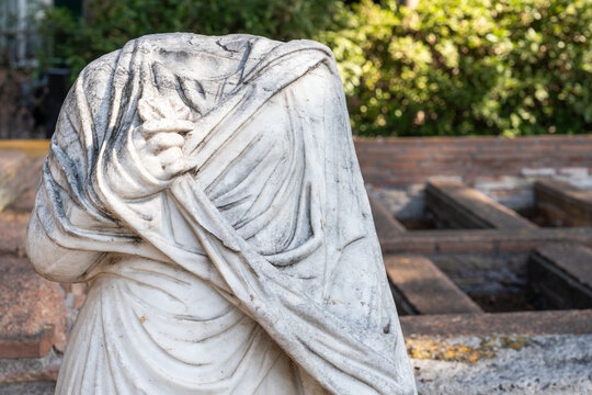 Close-up on headless ruin of ancient roman statue decorating a garden in Italy