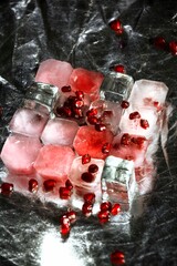 Ice cubes with pomegranate seeds on silver background