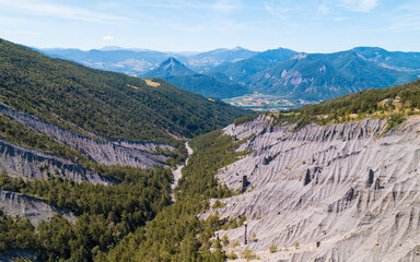 Fototapeta na wymiar Aerial photography by drone of the rock formations, the Demoiselles Coiffées in Serre-Ponçon and its mountains, located in the Hautes-Alpes in France