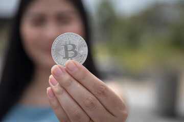 Smiling beautiful Female holding Bitcoin digital currency and cryptocurrency with blur background