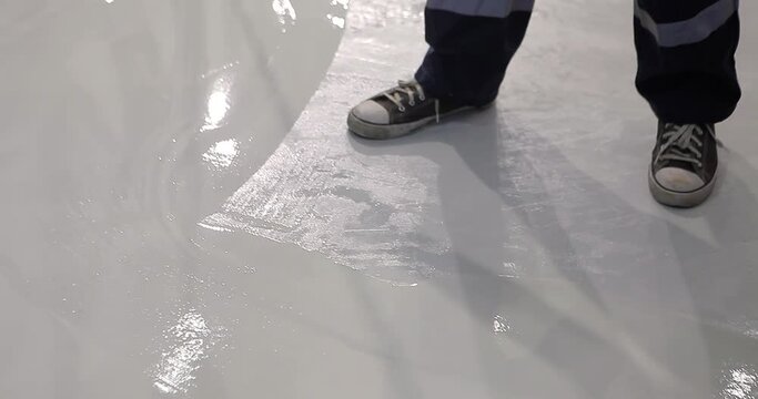 A builder distributes resin flooring material evenly using a Scraper Float. A builder is applying polymer floors using Scraper Float. The process of creating polymer floors