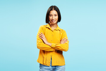 Portrait of smiling beautiful Asian woman, businesswoman wearing casual yellow shirt, arms crossed