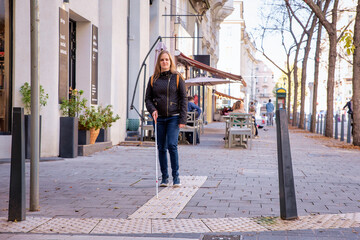 Full length of blind woman with white cane walking on the street