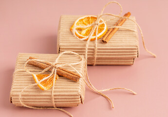 Craft carton recyclable gift boxes tied up with string bow decorated with dried orange citrus fruit slice and cinnamon stick on brown background used as eco friendly organic holiday present decoration