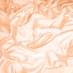 Fototapeta premium Waves and patterns of crumpled natural satin fabric. Color of the year 2024 Peach Fuzz