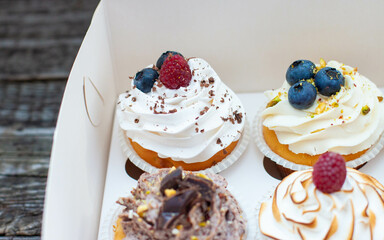 Assorted cupcakes in gift box with chocolate, vanilla and oreo cream, whipped meringue, raspberry, blueberry and bites of chocolate