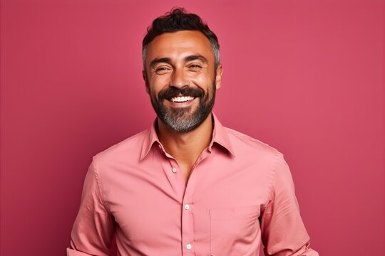 Portrait of a handsome bearded Indian man in a pink shirt on a pink background