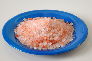 Fototapeta na wymiar pink sea salt lies by the handful in a blue deep plate, top view, health concept