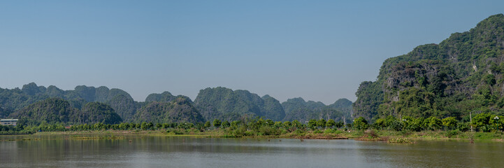 Fototapeta na wymiar Panoramic views of Ninh Binh Countryside with Green mountains, blue skies and rice fields in Vietnam