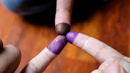 Three inked pinky fingers of a family put together. Purple ink blots from many voters' fingers...