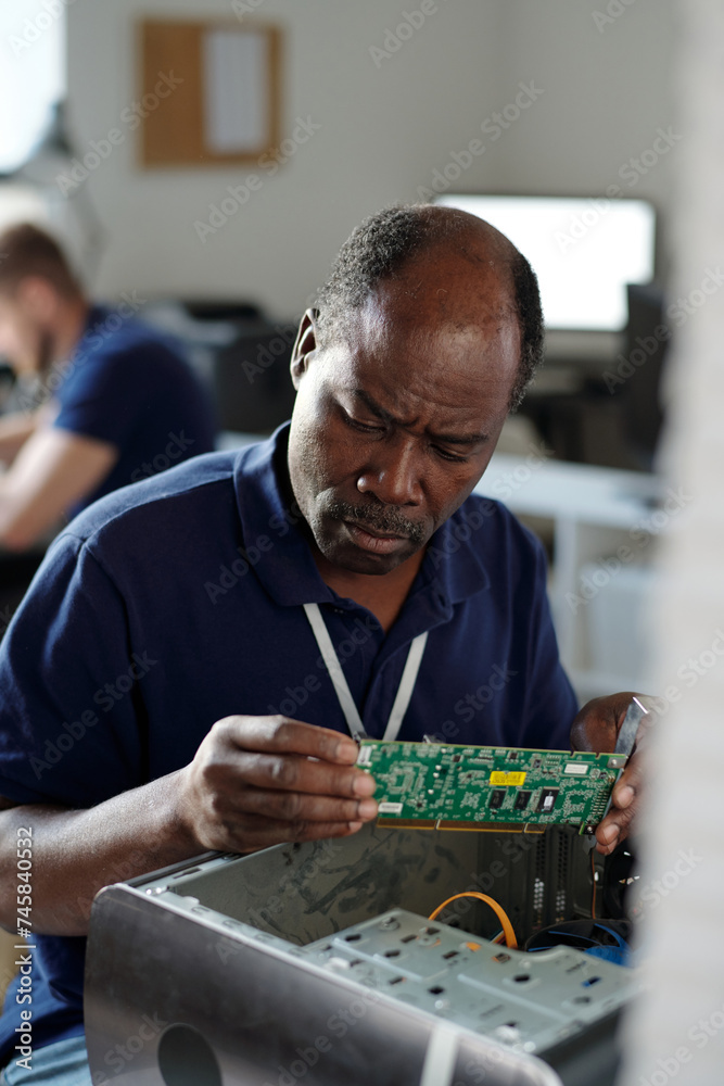 Poster experienced african american engineer of repair service office looking at computer motherboard while