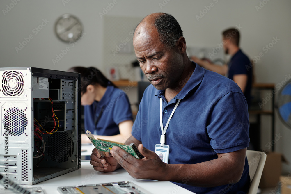 Poster Experienced technician or worker of repair service office looking at computer motherboard while checking parts of processor