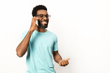 Portrait of African American man engaging in a casual phone conversation, isolated on a white background. Conveys happiness, technology use, and communication. - 745847304