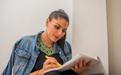 mujer joven universitaria sentada leyendo un texto en el campus  - obrazy, fototapety, plakaty