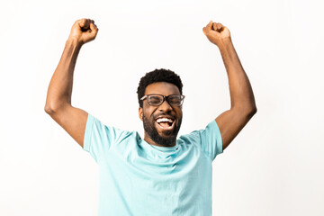 African American man with glasses celebrating a victory, arms raised in excitement, isolated on a white background, conveying happiness and positive emotions. - 745848701