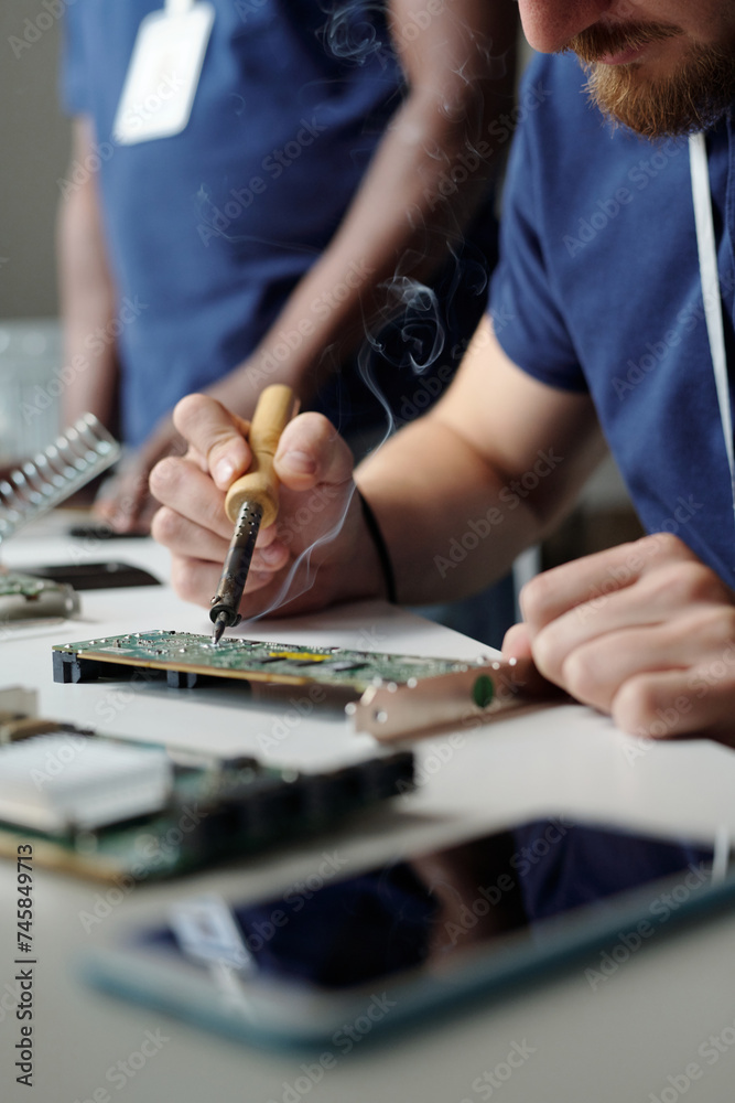 Poster Close-up of young technician of maintenance service using electric handtool while repairing part of computer processor by workplace