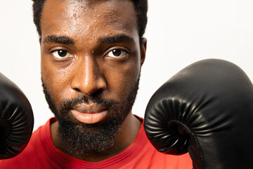 Close-up of a determined African American man with boxing gloves, showcasing concentration and resilience. Perfect for fitness and motivational themes. - 745852196