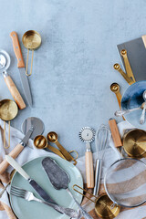 various kitchen utensils are laid out in an arc on a striped kitchen towel on a gray concrete background. sieve, measuring spoons, knives, pizza cutter. space for text