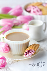 An elegant cup of tea served with a decorated Madeleine for Mother's Day.
