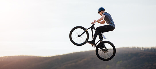Young man flying through the air on a mountain bike - obrazy, fototapety, plakaty