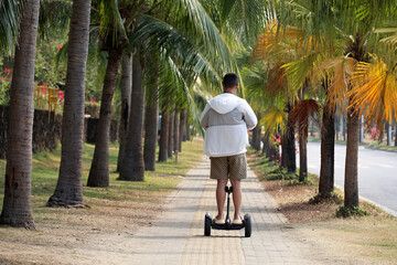 Man rides a gyro scooter on a city street on palm trees background