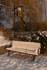 Snow Covered Park Bench At Sunset - 745864156