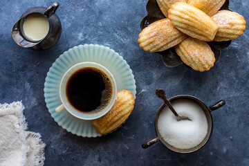 A cup of coffee served with traditional French Madeleines