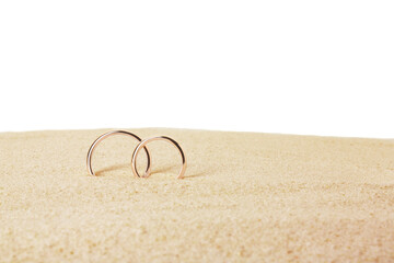 Fototapeta na wymiar Honeymoon concept. Two golden rings and sand isolated on white