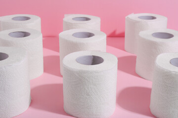 Many soft toilet paper rolls on pink background, closeup