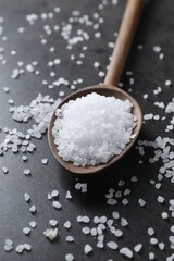 Natural salt and wooden spoon on black table