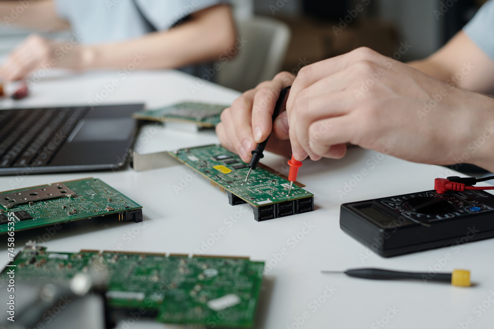 Poster unrecognizable technician of repair service center with electric handtool checking motherboard and i
