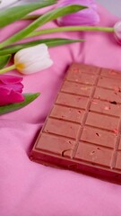 A bar of pink ruby chocolate with sublimated freeze-dried strawberries and almonds and spring tulip...