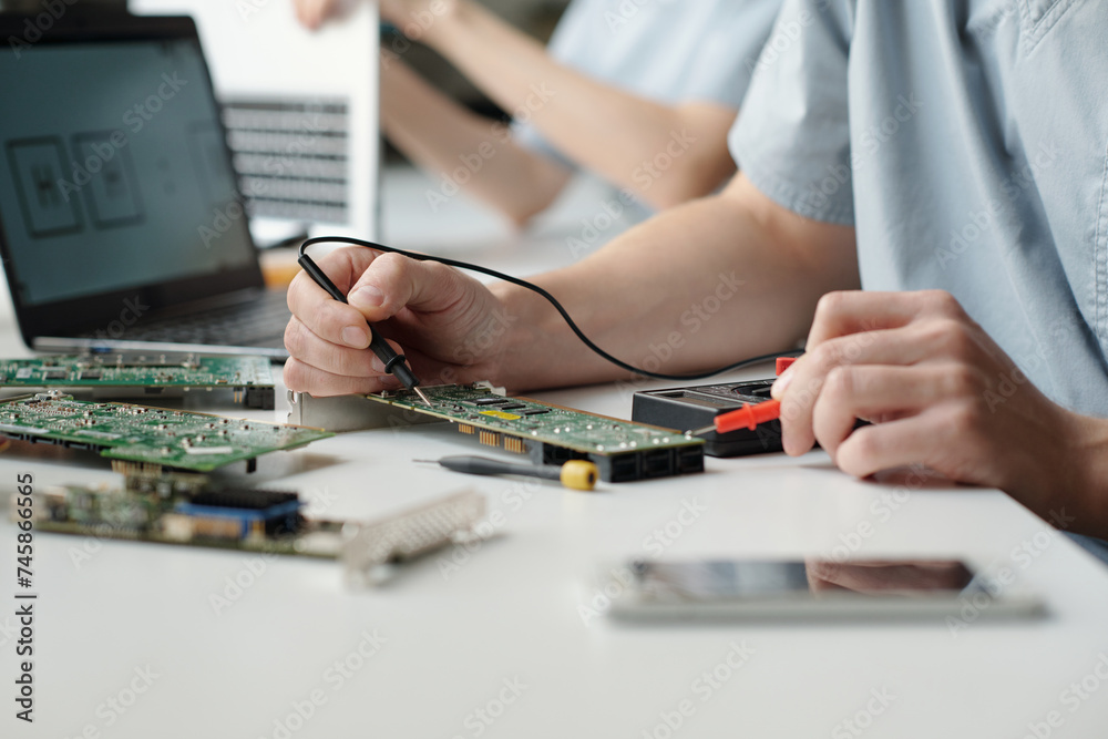 Poster Hands of young worker of troubleshooting service center using electric handtool while checking and repairing computer motherboard