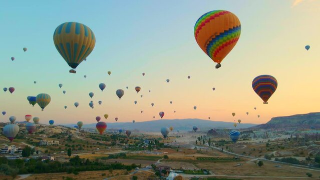 Aerial video. Captured against the canvas of the Cappadocian sky, this video showcases the enchanting spectacle of a hot air balloon festival. The vibrant balloons rise gracefully over the valleys of