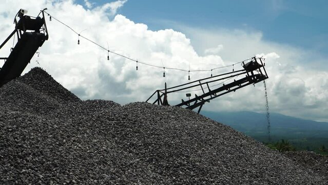 gravel from a natural stone crushing machine in piles with a background of sky and mountains