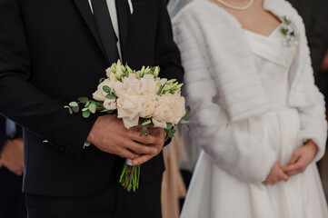 A beautiful wedding bouquet in the hands of the groom. Bouquet with white roses in the hands of the groom