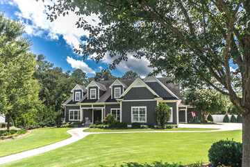 Fototapeta na wymiar A large gray craftsman new construction house with a landscaped yard and leading pathway sidewalk