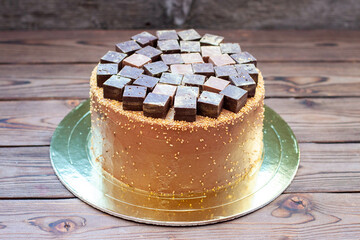 Chocolate brownie cake decorated with candy bars and truffles on rustic background. Cake for chocolate lovers