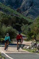 Fototapeta na wymiar Young and Mid Adult Friends Cycling Up Rural Mountain Road, Alicante, Costa Blanca, Spain - stock photo